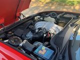 a red car with its hood open and a cell phone in the trunk