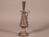 un vase en argent posé sur un socle en métal