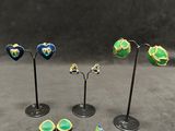 a set of three small metal flower stands with green, blue, and yellow flowers