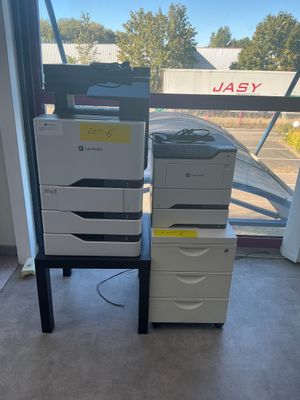 a stack of printer ' s sitting on a table in front of a window