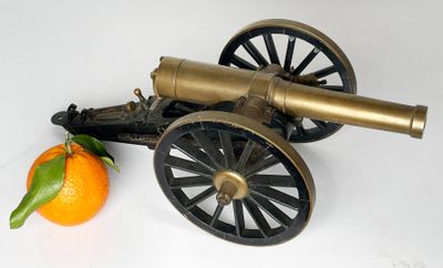 an old cannon and an orange on a white surface