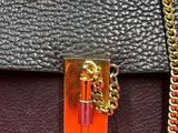 a close up of a black and red purse with a gold chain