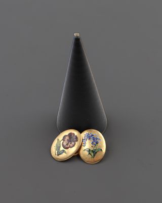 une paire de boucles d'oreilles ornées de fleurs, posées sur un cône noir