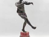 statue en bronze représentant un homme tenant une raquette de tennis, posée sur un socle en marbre