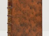 un vieux livre à la couverture marron posé sur une table blanche