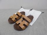 the brown sandals are on the bed next to a white towel