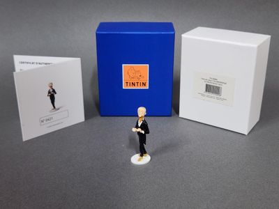 une petite figurine représentant un homme en smoking, à côté d'une boîte bleue