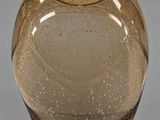 une image représentant un vase en verre brun posé sur une surface grise