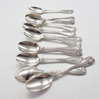 six cuillères en argent sont alignées sur une surface blanche