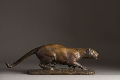 bronze statue of a panther on a wooden base