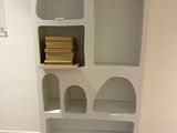 une bibliothèque blanche avec des livres dessus, dans une pièce