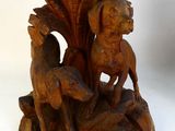 a wooden sculpture of a dog and a bird on a rock