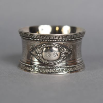 an antique silver napkin ring with a monogram on the front