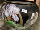 un vase noir orné de fleurs violettes, exposé dans une vitrine