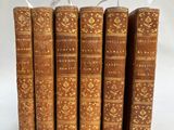 cinq vieux livres sont alignés sur une surface blanche