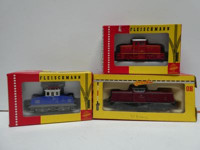 three toy trains are in boxes on a white surface