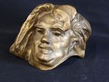 bronze sculpture of a man ' s face on a black background