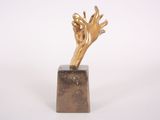 bronze sculpture of a hand reaching out of a block on a white background
