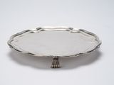 a silver plate with a tassel on it sitting on a table