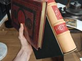 a person holding a book that is on top of a table