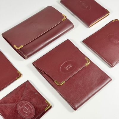 six portefeuilles en cuir rouge rehaussés de détails dorés sur fond blanc