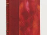 a red book sitting on top of a white table next to a white wall