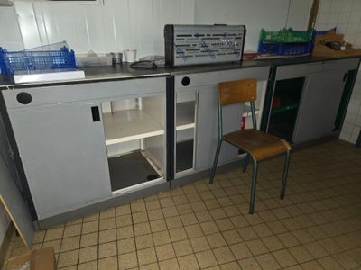 a small kitchen with a refrigerator and a chair in it
