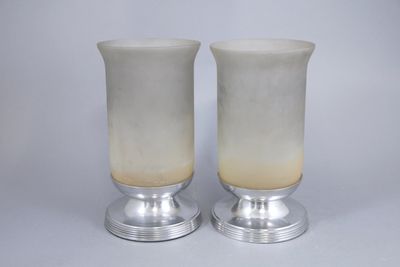 une paire de vases en verre blanc posés sur un socle en métal
