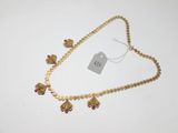 un gros plan d'un collier en or orné de perles rouges sur un fond blanc
