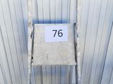une échelle métallique sur laquelle est accrochée une pancarte, devant un immeuble