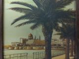 painting of a palm tree in front of a body of water with a building in the background