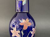 un vase en verre bleu orné de fleurs et de papillons peints