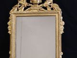 un miroir en or richement décoré, surmonté d'un oiseau