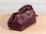 the burgundy leather clutch bag is sitting on a wooden table