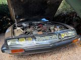 a car with its hood open sitting in the dirt
