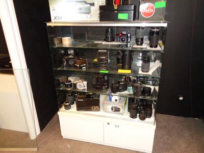 une vitrine sur laquelle sont disposés de nombreux appareils photo, dans une pièce