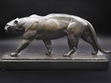 statue d'une panthère posée sur un socle de marbre, sur fond noir