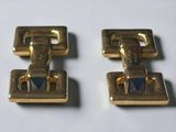 pair of gold tone cufflinks with a blue stone in the center
