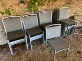 six chairs and a table in front of a stone wall
