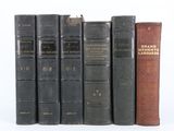 Plusieurs livres anciens sont alignés sur une étagère devant un fond blanc
