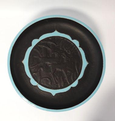 une assiette noire et bleue sur laquelle figure l'image d'un homme à cheval