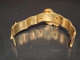 a close up of a gold bracelet on a black surface