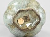 a small green vase with a coin in the middle of it