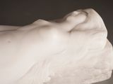 a statue of a woman laying down on a rock
