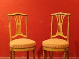 une paire de chaises anciennes adossées à un mur rouge dans une pièce vide