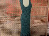 green dress on a mannequin stand in front of a woven wall