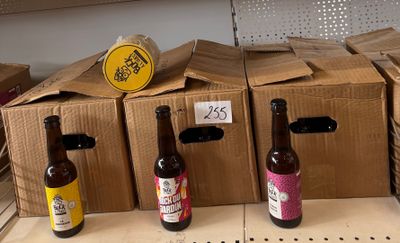 Plusieurs bouteilles de bière sont alignées sur une étagère dans un magasin.