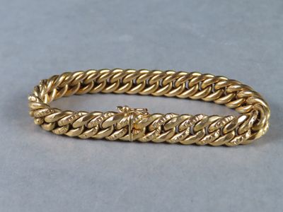a close up of a gold bracelet on a gray surface
