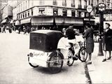 a vintage photo of a man on a bicycle pulling a cart