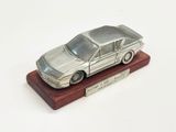 une maquette de voiture en argent posée sur un socle en bois